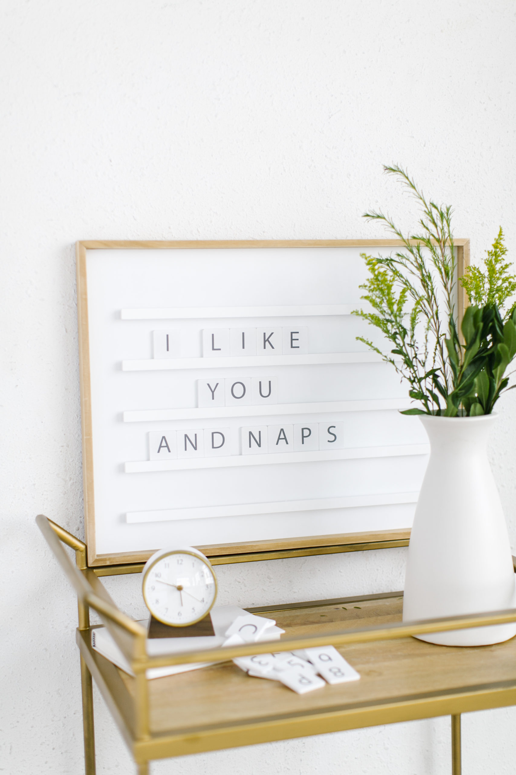A letter board on a cart with fresh flowers and a clock.