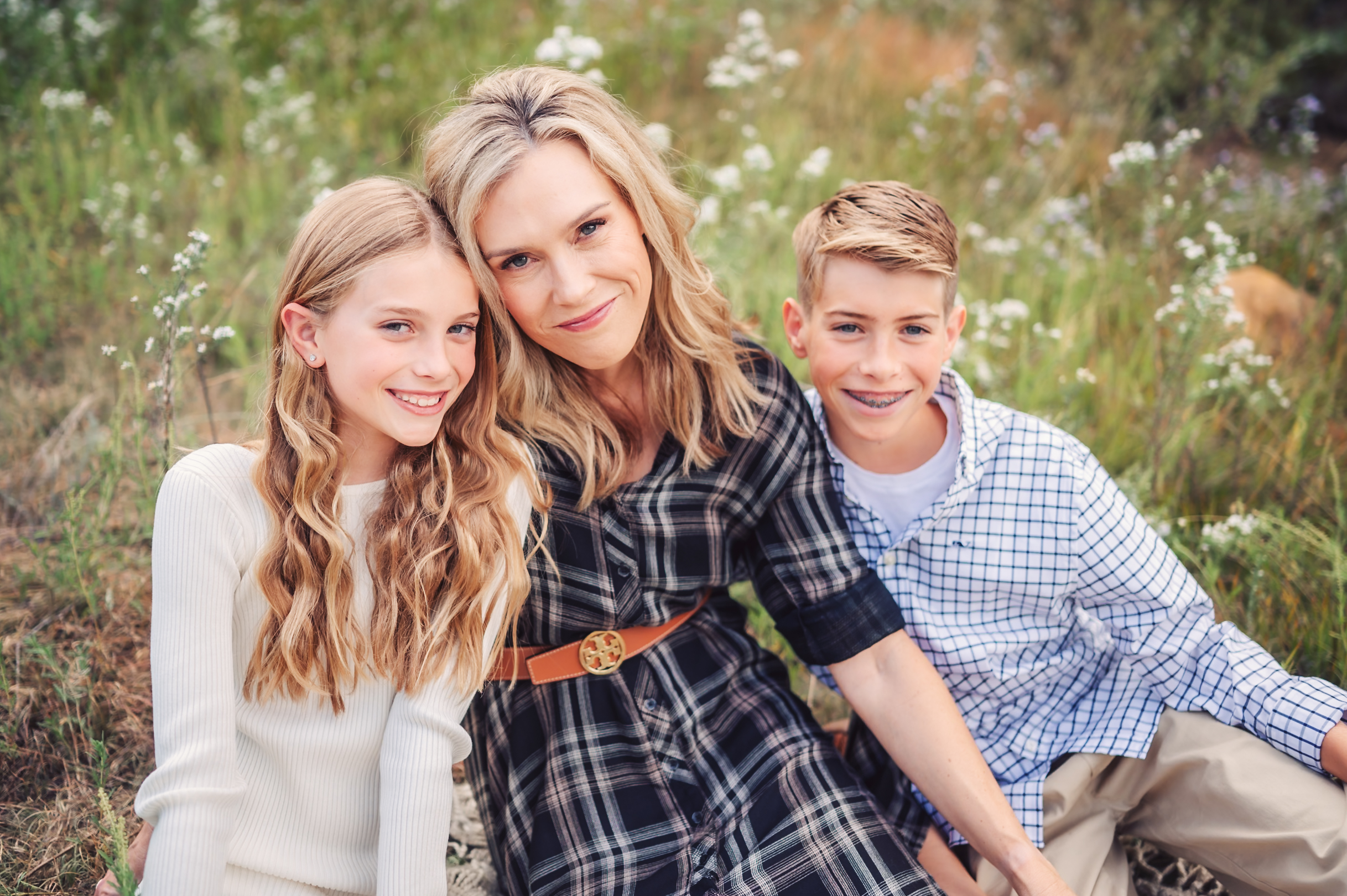 Mom and her two children having their photo taken in a field of wildflowers.