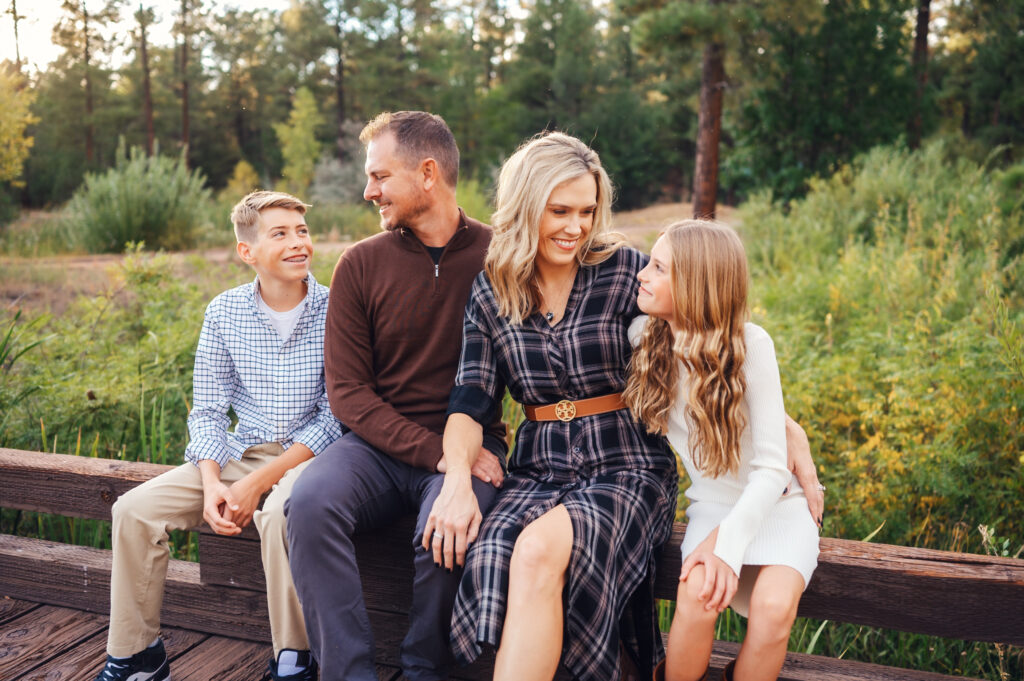 A family sitting on a wooden bridge, having their photo taken by Katelyn McKenzie Photography, who hired Amy Leigh Creative as her private photo editor.
