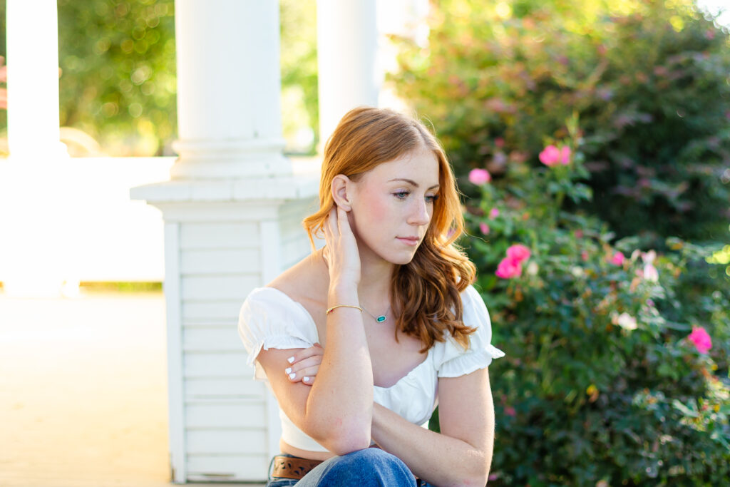 a high school senior sitting outside on the porch, posing for photos that will be used for blogging.